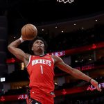 休士頓火箭隊球員（紅色球衣，1號）在 NBA 比賽中完成單手扣籃，展現空中對抗能力。