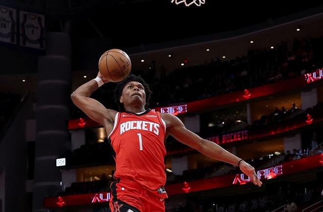 休士頓火箭隊球員（紅色球衣，1號）在 NBA 比賽中完成單手扣籃，展現空中對抗能力。