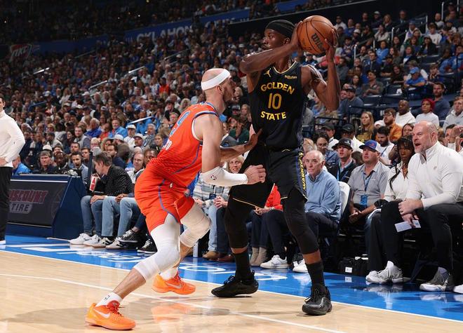 金州勇士队身穿黑色球衣的球员 (10号) 在比赛中持球面对俄克拉荷马雷霆队防守球员的压迫，突出勇士在半场44-63落后雷霆的激烈对抗。