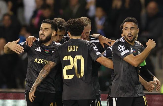 一群身穿黑色和金色球衣的卡拉巴赫(Qarabag)足球运动员在球场上拥抱庆祝进球的特写镜头。