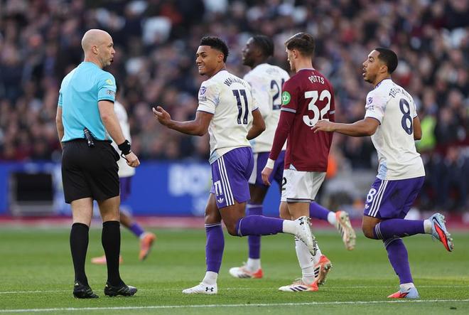 阿斯顿维拉球员（身穿白色球衣，在英超比赛中与裁判进行交流，庆祝或讨论进球。