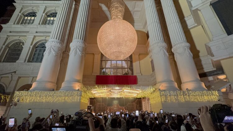 澳门十六浦赌场（Ponte 16）于 11 月 28 日正式停止运营，结束 17 年历史。图片展示了夜晚灯火通明的赌场外部，巨大的吊灯和古典立柱下，大量人群举起手机拍照记录这一历史性时刻。此图象征澳门卫星赌场重组背景下十六浦关闭的关键一步。