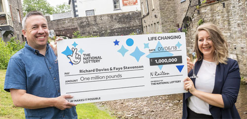 夫妇手持英国乐透巨型支票合影