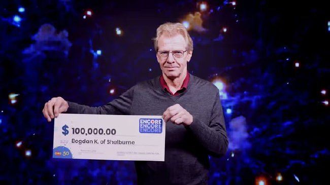 男性中奖者手持Encore十万加元支票合影