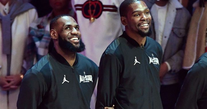 NBA 全明星活动现场，两名身穿黑色全明星训练服的球员并肩微笑站立