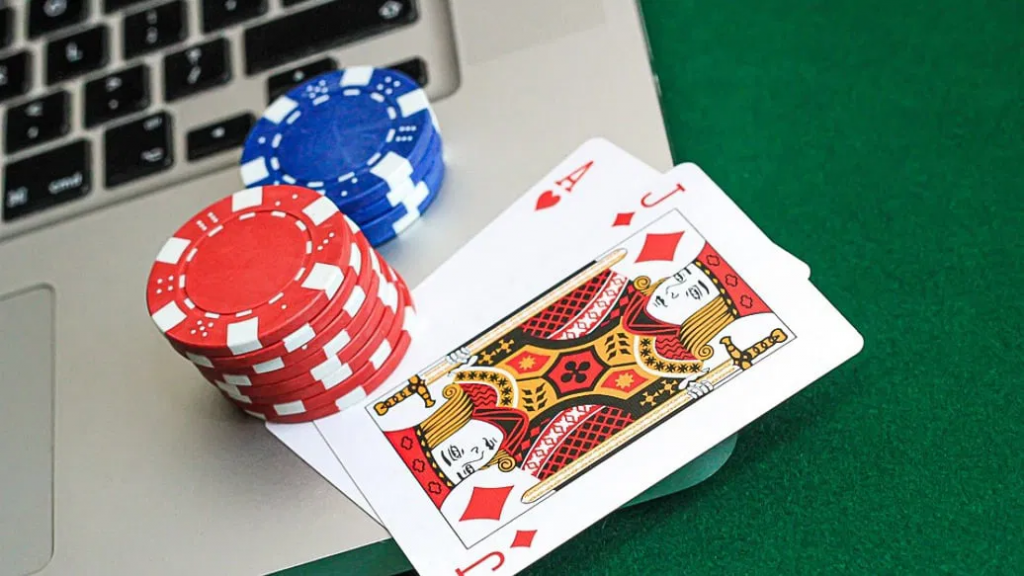 笔记本电脑旁摆放筹码与扑克牌的在线博彩示意画面