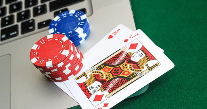 笔记本电脑旁摆放筹码与扑克牌的在线博彩示意画面