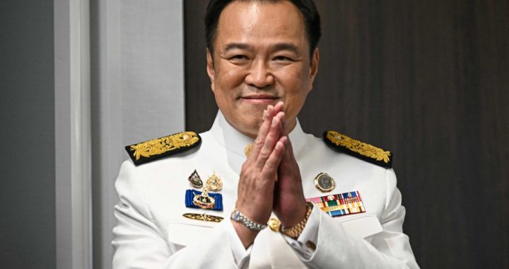 泰国总理阿努廷身着白色礼服双手合十致意画面