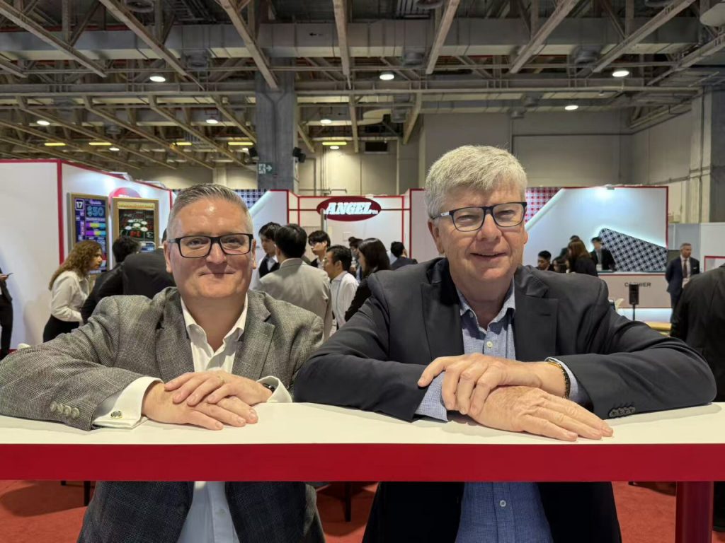 Angel Australasia负责人Bryan Jenkins与顾问Laurent Fresnel在G2E Asia展位合影,介绍智能赌枱技术布局