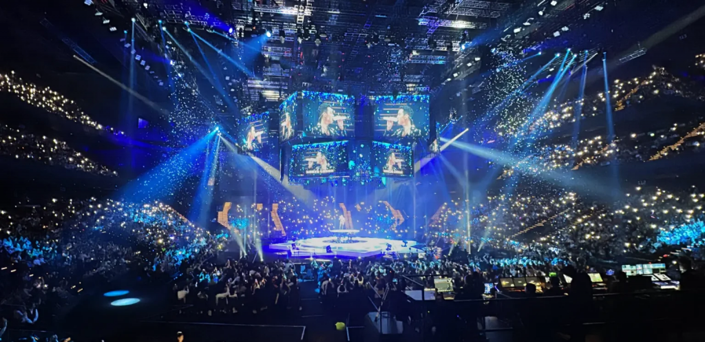 大型演唱会场馆灯光与观众席画面，澳门非博彩娱乐活动持续扩张