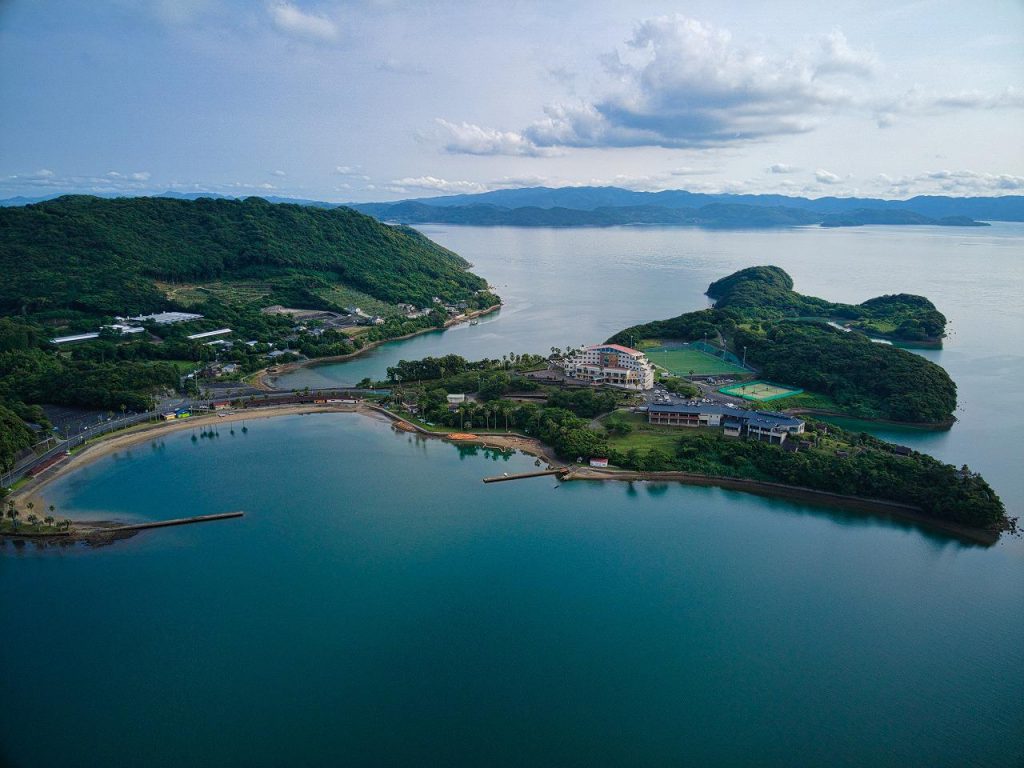 长崎县大村湾周边航拍景色，海湾、岛屿与沿岸建筑展现潜在IR选址环境
