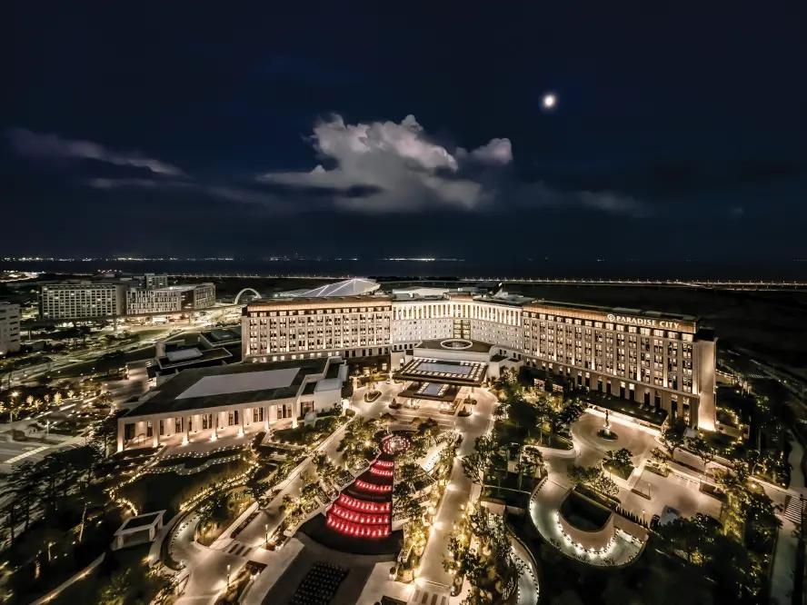 韩国仁川百乐达斯城夜景航拍图，建筑群灯光亮起，展示综合度假村与周边景观