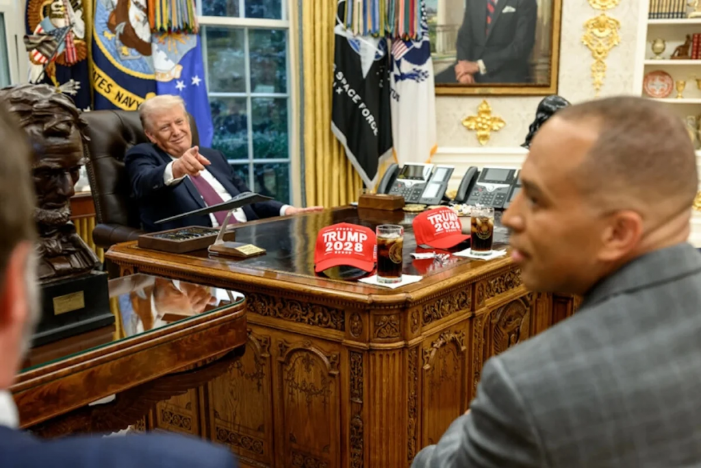 特朗普在白宫椭圆形办公室会见来宾，桌上摆放印有Trump 2028字样的红色帽子