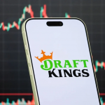 手机屏幕显示DraftKings标志，背景为红绿交织的股价走势图