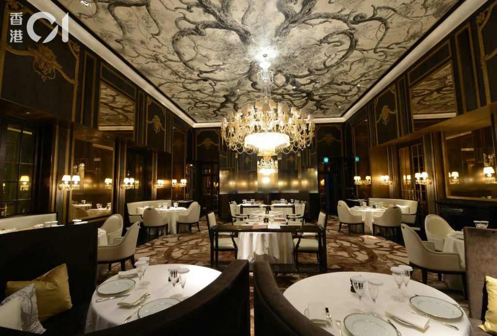 十三皇宫高端餐厅采用深色墙面、水晶吊灯与独立桌席布局