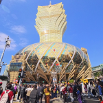 澳门新葡京酒店外观与游客人潮，展现澳门5月博彩收入增长和赌场股上涨背景