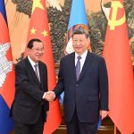 习近平与洪森在中柬两国国旗背景前握手合影