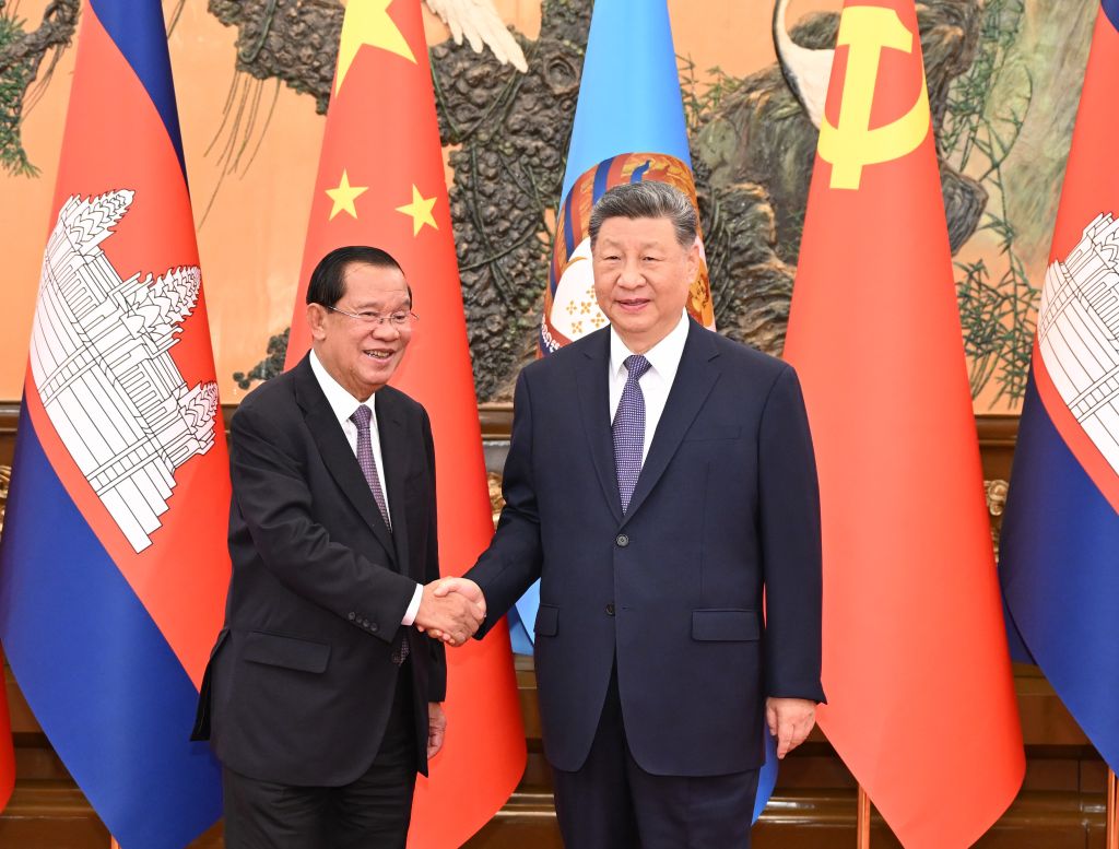 习近平与洪森在中柬两国国旗背景前握手合影