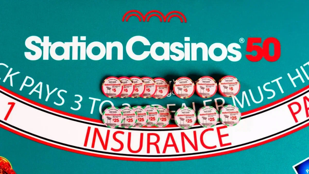 在绿色的廿一点博彩桌面上摆放着两排印有Red Rock和Station Casinos 50周年字样的纪念娱乐场筹码